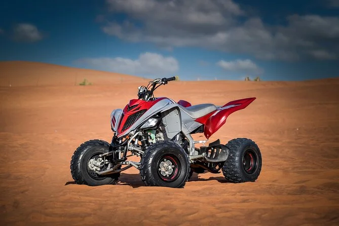 A red sport quad bike parked on desert sand